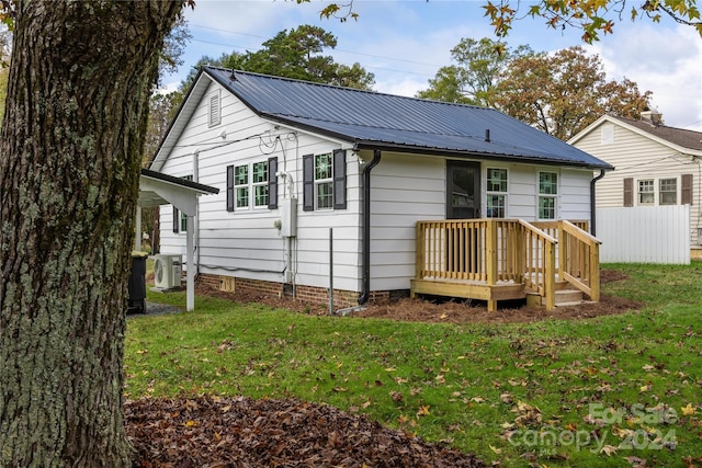 rear view of property featuring a lawn, ac unit, and a wooden deck