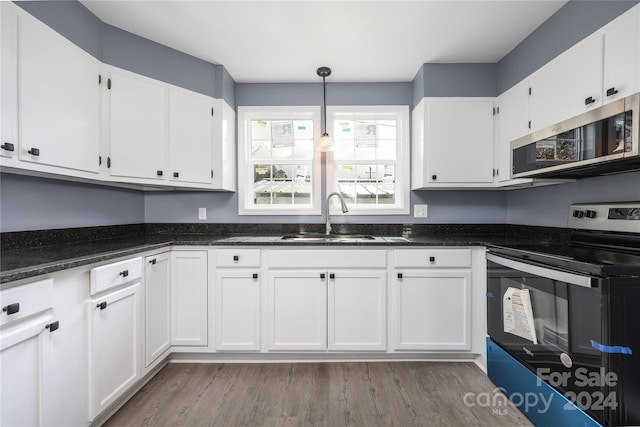 kitchen featuring dark wood-type flooring, white cabinets, sink, pendant lighting, and appliances with stainless steel finishes