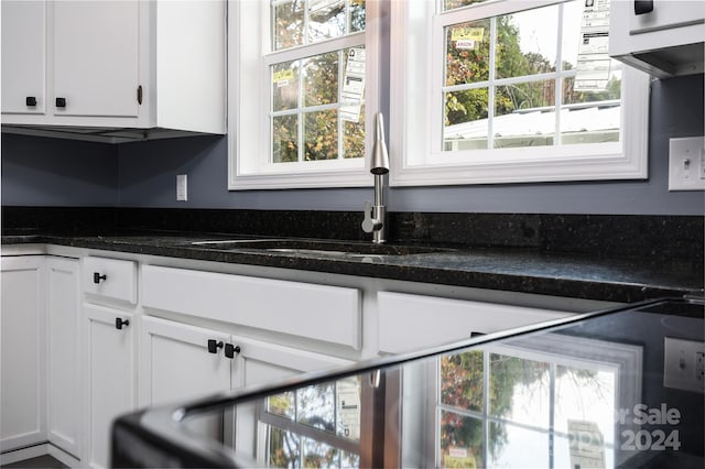 kitchen with white cabinets, dark stone countertops, and sink