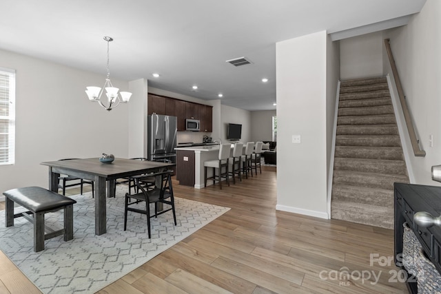 dining room with light hardwood / wood-style floors and a notable chandelier