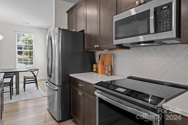 kitchen featuring dark brown cabinetry, light wood-type flooring, and appliances with stainless steel finishes