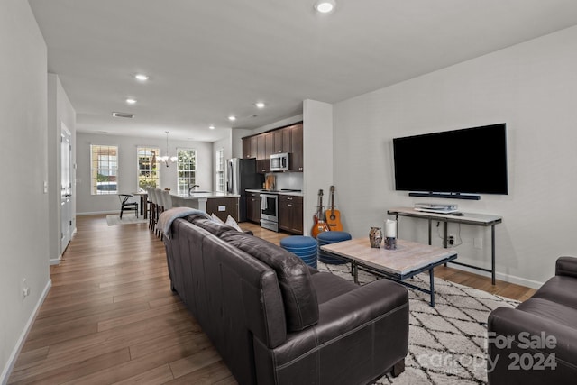 living room featuring light wood-type flooring and a notable chandelier