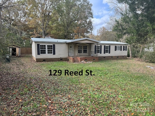 manufactured / mobile home featuring covered porch, a front yard, and a storage unit