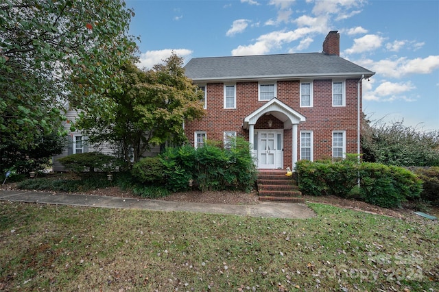 colonial inspired home featuring a front lawn