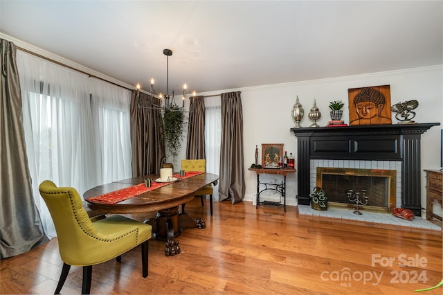 dining room featuring a chandelier, hardwood / wood-style flooring, ornamental molding, and a brick fireplace