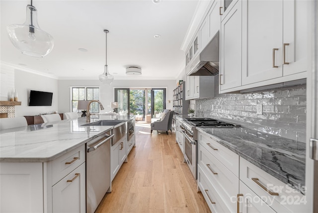 kitchen with white cabinets, ventilation hood, decorative light fixtures, and stainless steel appliances