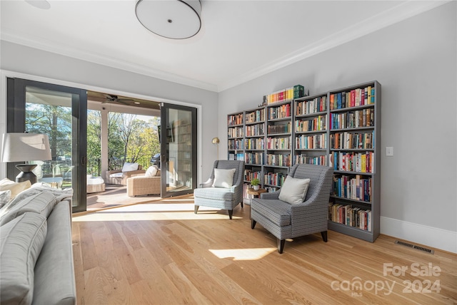 sitting room with crown molding and light hardwood / wood-style flooring