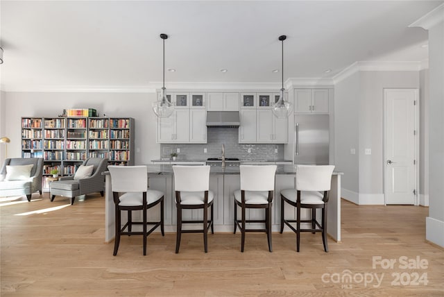 kitchen featuring decorative light fixtures, a kitchen island with sink, and light hardwood / wood-style floors