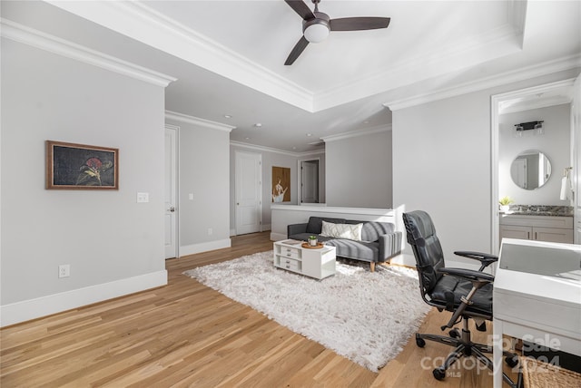 home office with ceiling fan, a raised ceiling, crown molding, and light hardwood / wood-style flooring