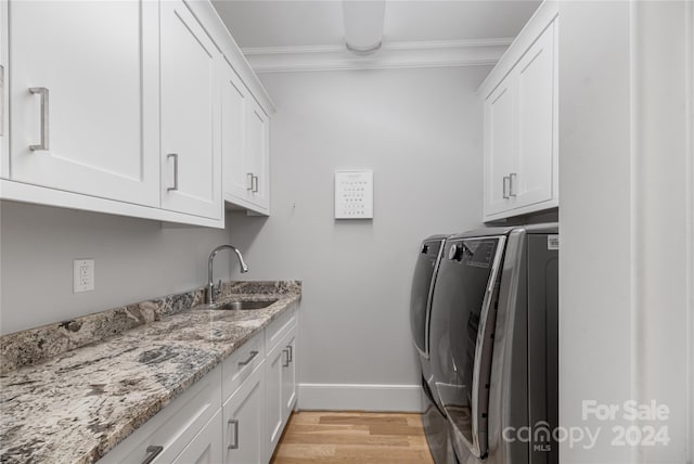 clothes washing area featuring cabinets, crown molding, sink, independent washer and dryer, and light wood-type flooring