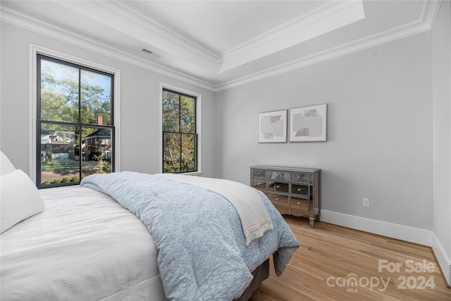 bedroom with a raised ceiling, crown molding, and hardwood / wood-style floors