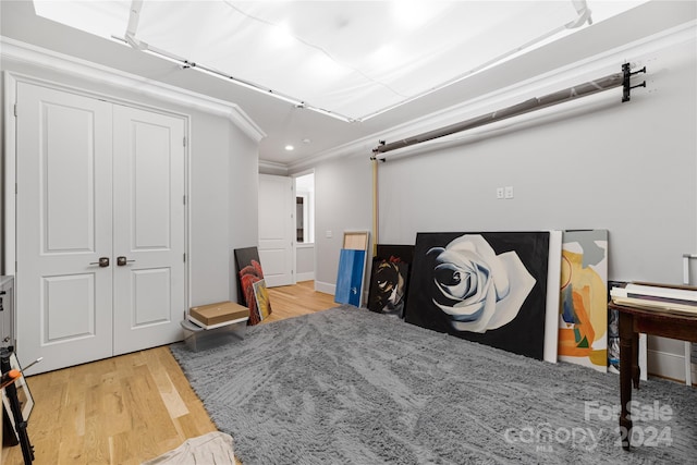 bedroom featuring hardwood / wood-style flooring, ornamental molding, and a closet