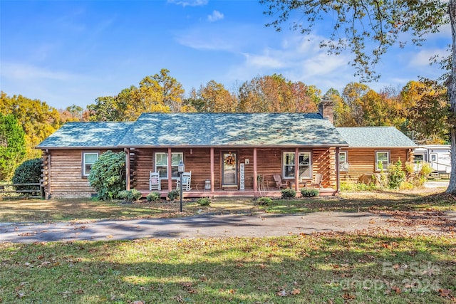 log-style house featuring covered porch and a front yard