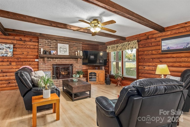 living room with beam ceiling, rustic walls, ceiling fan, light hardwood / wood-style flooring, and a textured ceiling