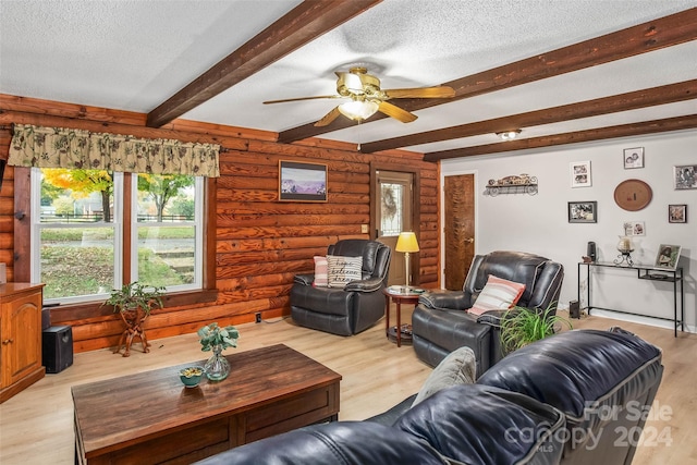 living room with beam ceiling, ceiling fan, light hardwood / wood-style flooring, and a textured ceiling