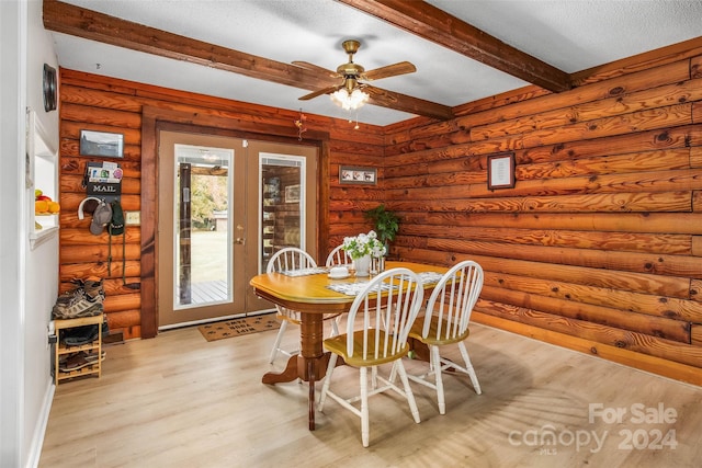 dining room featuring ceiling fan, light hardwood / wood-style flooring, log walls, and beamed ceiling