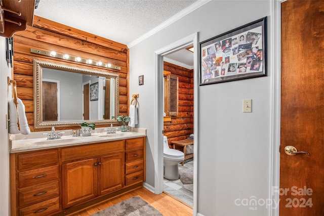 bathroom featuring vanity, hardwood / wood-style flooring, toilet, ornamental molding, and a textured ceiling