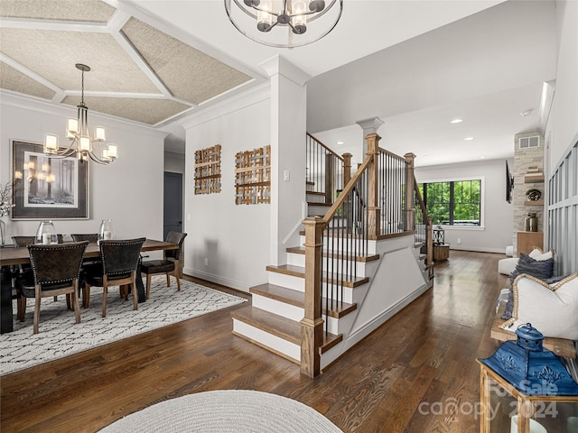 dining room with dark wood-type flooring, a notable chandelier, crown molding, and decorative columns