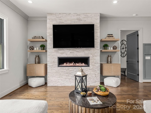 living room with a fireplace, dark wood-type flooring, and crown molding