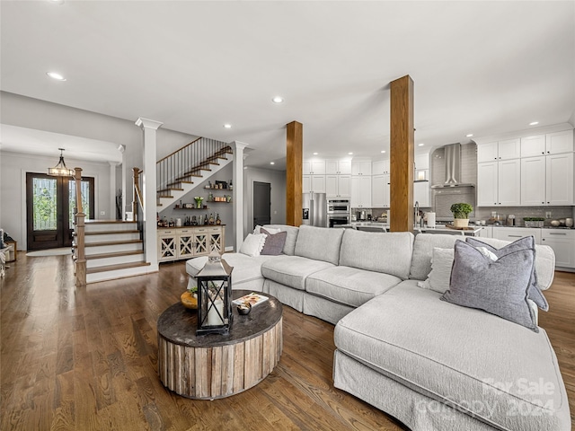 living room featuring ornate columns, a notable chandelier, and dark hardwood / wood-style floors