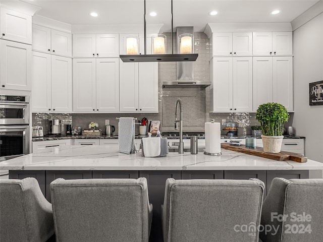 kitchen featuring light stone counters, decorative light fixtures, a kitchen bar, and a spacious island