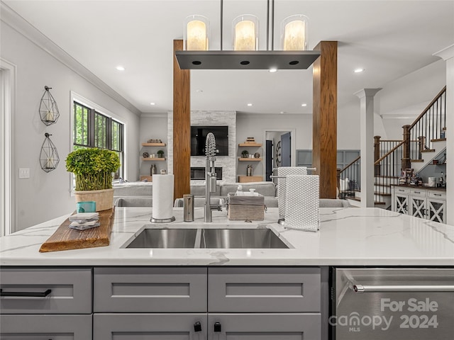 kitchen featuring gray cabinetry, sink, light stone counters, and crown molding