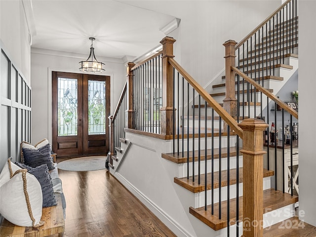 entryway featuring an inviting chandelier, hardwood / wood-style floors, crown molding, and french doors