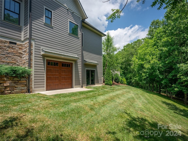 view of side of property with a garage and a lawn