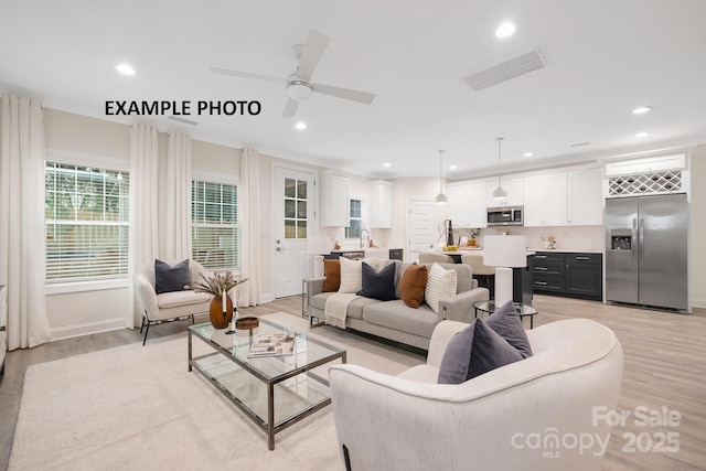 living room with light hardwood / wood-style floors, ceiling fan, and sink