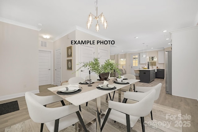 dining area featuring a notable chandelier, light wood-type flooring, and crown molding