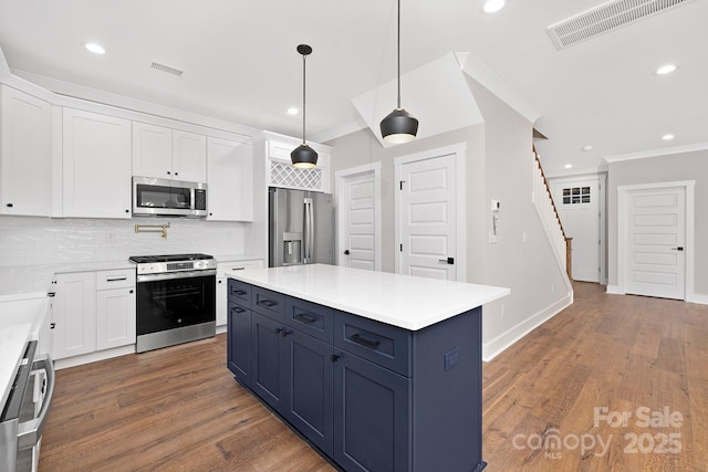 kitchen featuring tasteful backsplash, ornamental molding, stainless steel appliances, white cabinetry, and hanging light fixtures