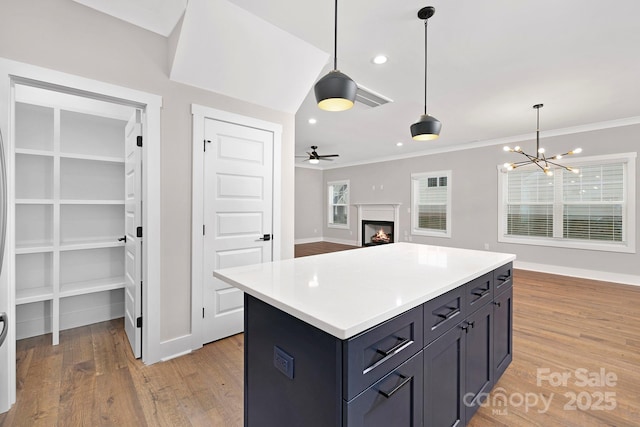 kitchen with a kitchen island, hanging light fixtures, ceiling fan with notable chandelier, and ornamental molding