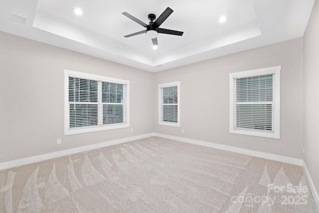 carpeted spare room with a tray ceiling and ceiling fan