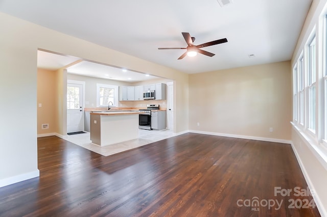 kitchen with wood-type flooring, a kitchen island, white cabinetry, appliances with stainless steel finishes, and sink