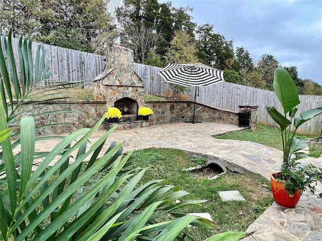 view of yard with an outdoor stone fireplace and a patio area