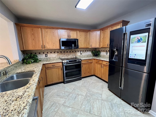 kitchen with decorative backsplash, appliances with stainless steel finishes, light stone counters, sink, and light tile patterned floors