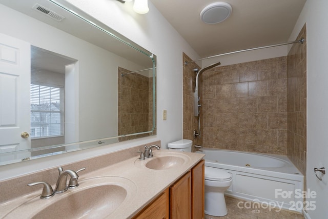 full bathroom featuring tile patterned floors, vanity, tiled shower / bath combo, and toilet