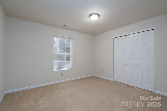 unfurnished bedroom with light carpet and a closet