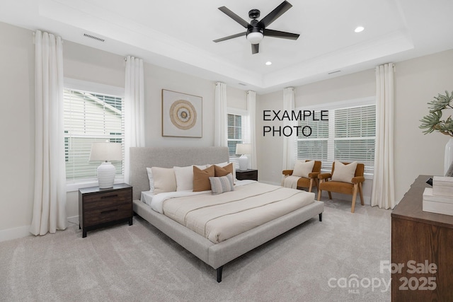 bedroom with ceiling fan, a raised ceiling, and light colored carpet