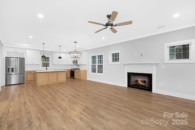 unfurnished living room featuring light hardwood / wood-style flooring, ceiling fan, and ornamental molding