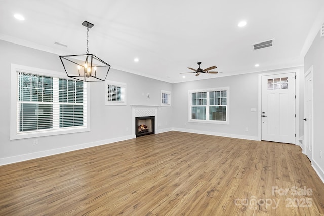 unfurnished living room with crown molding, ceiling fan with notable chandelier, and light wood-type flooring