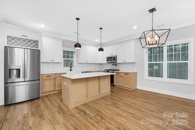 kitchen featuring pendant lighting, white cabinets, crown molding, a kitchen island, and stainless steel appliances