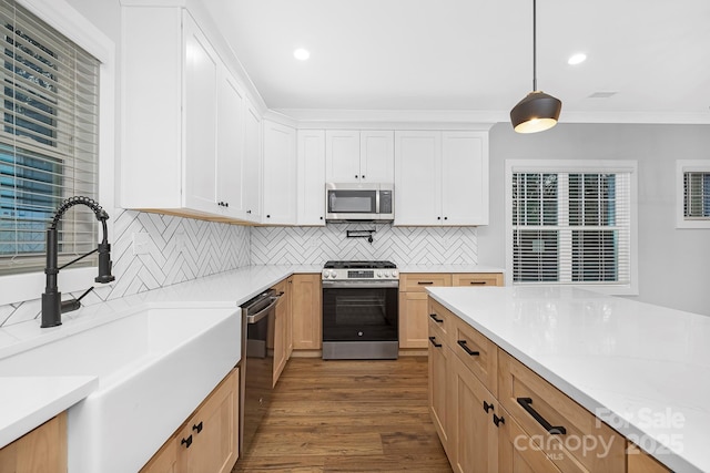 kitchen featuring tasteful backsplash, stainless steel appliances, sink, pendant lighting, and white cabinetry