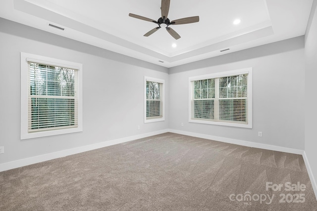 empty room featuring carpet, a raised ceiling, and ceiling fan