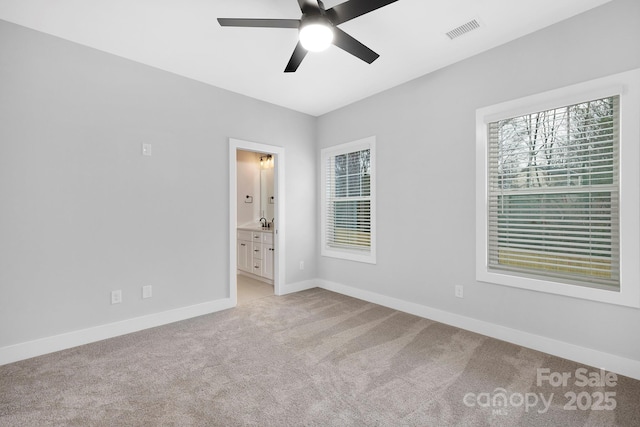 unfurnished bedroom featuring light colored carpet, ensuite bath, ceiling fan, and sink