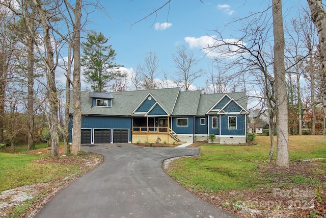 view of front of property featuring a front yard, covered porch, and a garage