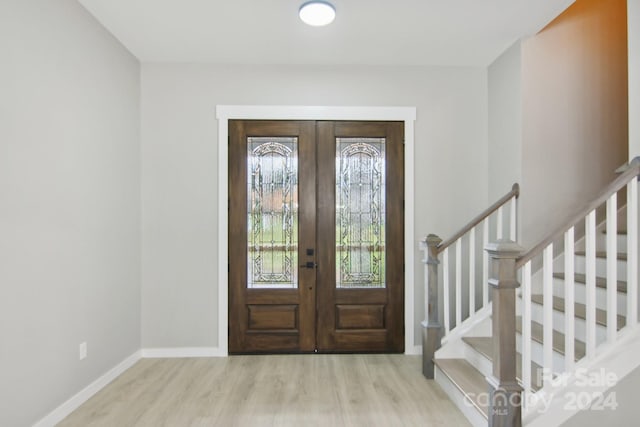 foyer entrance with french doors and light hardwood / wood-style floors