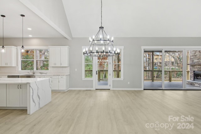 kitchen with white cabinets, hanging light fixtures, a healthy amount of sunlight, and light stone countertops