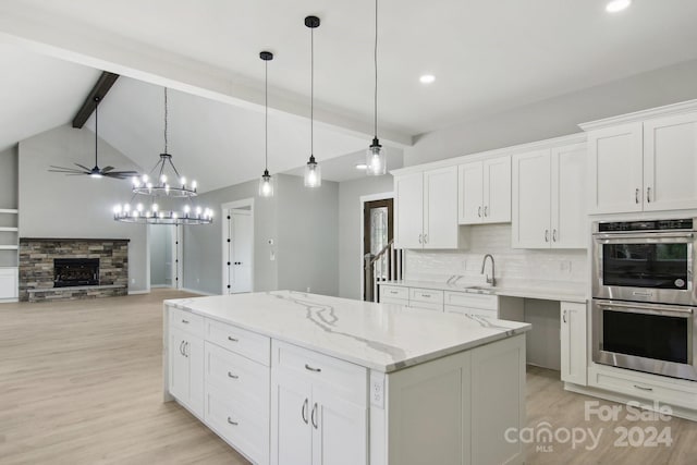 kitchen with stainless steel double oven, decorative light fixtures, light hardwood / wood-style floors, and white cabinets