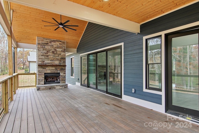 deck with ceiling fan and an outdoor stone fireplace